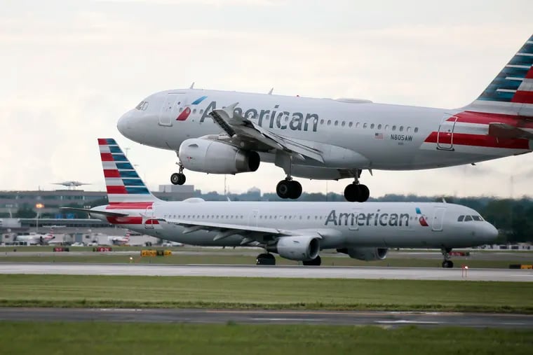 An American Airlines plane lands as another taxis to a runway at Philadelphia International Airport on July 18, 2019.