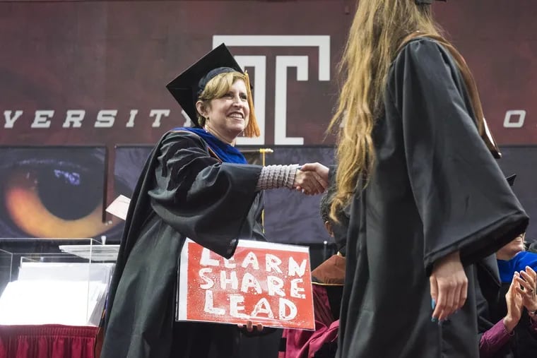 Tyler School of Art Dean Susan E. Cahan prepares to hand a piece of art to a new Temple graduate at the school's commencement ceremony last week.