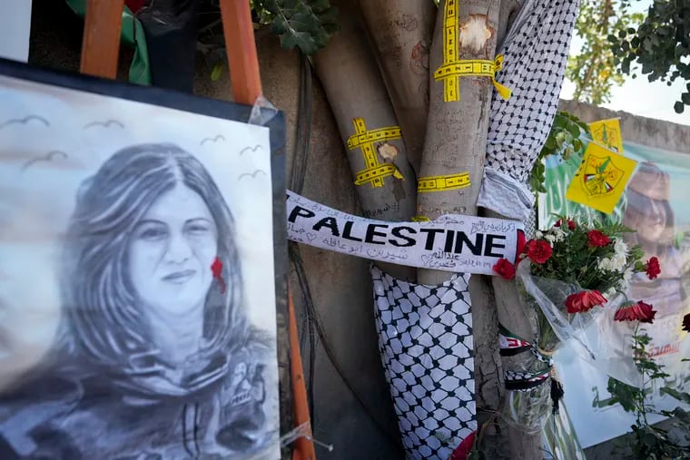 FILE - Yellow tape marks bullet holes on a tree and a portrait and flowers create a makeshift memorial, at the site where Palestinian-American Al-Jazeera journalist Shireen Abu Akleh was shot and killed in the West Bank city of Jenin, May 19, 2022.