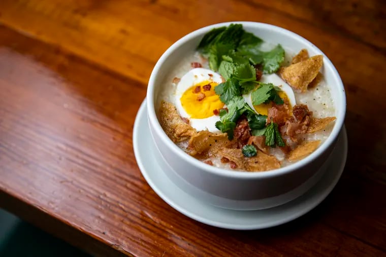 Chao Ga, a chicken broth rice porridge with a soft boiled egg, side of crispy chicken skin, bacon bits, and herbs, at The Breakfast Den in Philadelphia, Pa., on Friday Feb. 4, 2022.