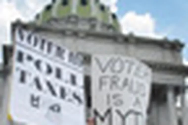 Demonstrators hold signs at an NAACP-organized rally on the steps of the Pennsylvania Capitol to protest the state's new voter identification law on Tuesday, July 24, 2012 in Harrisburg, Pa. The law is being challenged in court as unconstitutional. Democrats say it's an election year stunt to steal the White House. Republicans say it's necessary to prevent voting fraud. (AP Photo/Marc Levy)