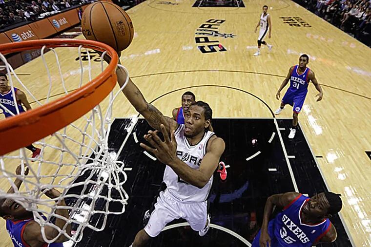 The Spurs' Kawhi Leonard over the 76ers' Elliot Williams and Henry Sims. (Eric Gay/AP)