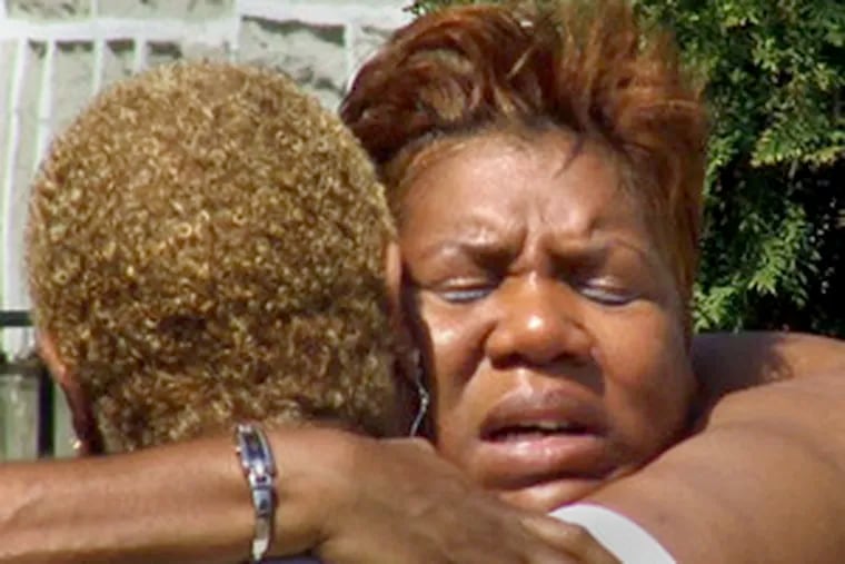 Two women embrace in grief over the news that a neighbor had been slain on Conlyn Street near Old York Road.