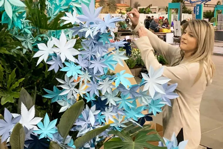 Sarah Seamonson, who works with the Conshohocken-based marketing agency called Chronic, prepares a display of paper cut to look like cannabis in the Greenroom at the Philadelphia Flower Show.