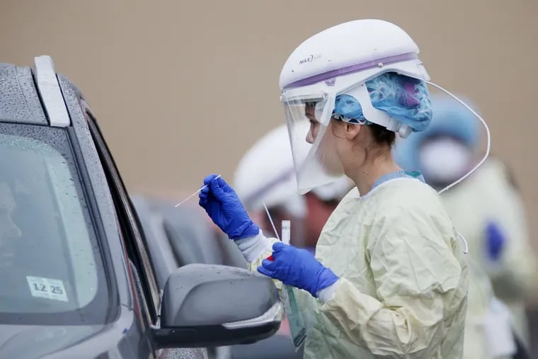 A medical worker collects samples from individuals who signed up for "drive-through testing" for the coronavirus at a Penn Medicine site in West Philadelphia in March.