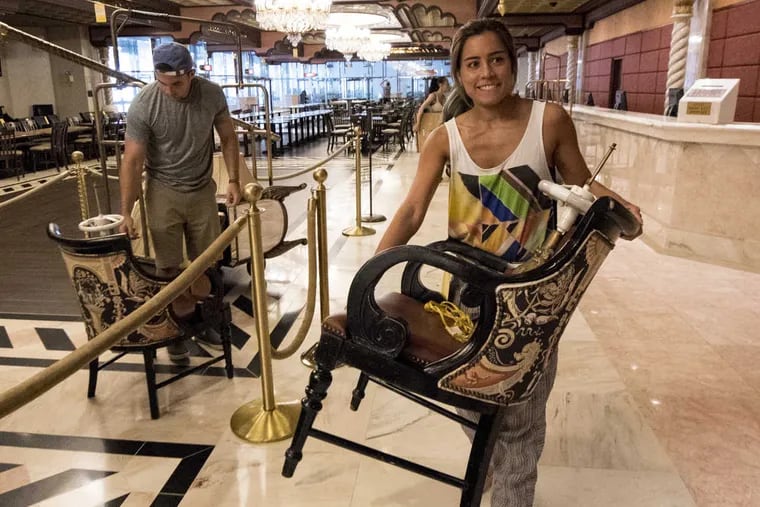 Kira Wong of Hoboken, NJ with chair at the Taj Mahal liquidation sale in Atlantic City on Thursday. In background is boyfriend Mike Kuhn.