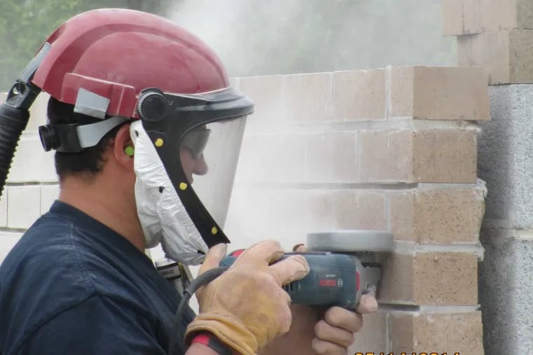 A union bricklayer, photographed at the Bricklayers and Allied Craft Workers Local 1’s training center, wears a mask to protect himself from silica dust as he demonstrates the unsafe way to drill into bricks.