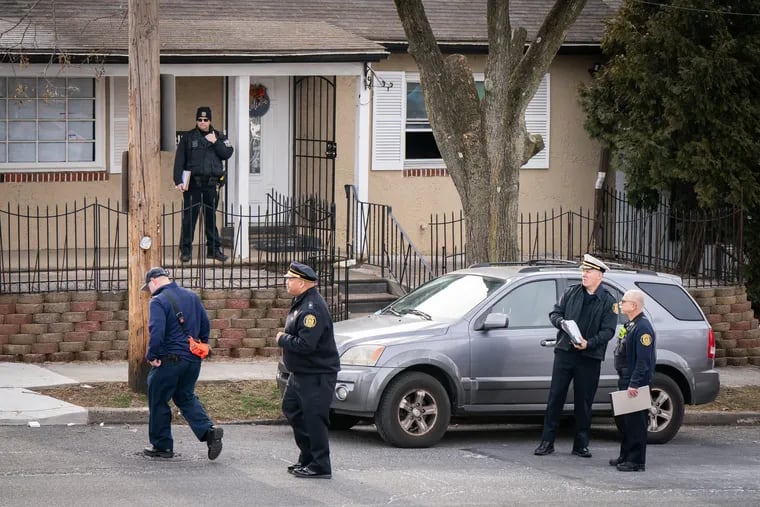 Officials investigate at the Ashburner Street home where three people were found dead in Philadelphia on Thursday.