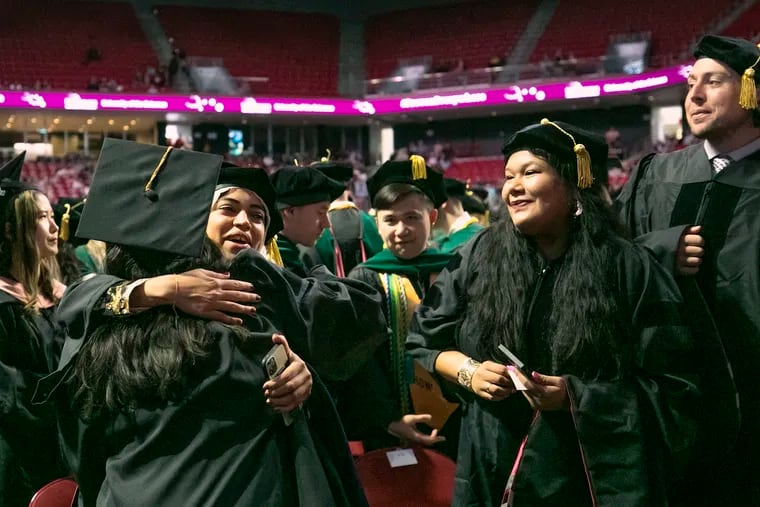 Graduates embrace during the University of the Sciences final commencement ceremony at the Liacouras Center in Philadelphia on Wednesday, May 25, 2022. The University of the Sciences will merge with St. Joseph's June 1.