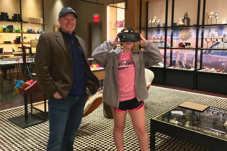 Carly Rosenberger, 13, of Conshohocken, takes the COACH Virtual Reality tour of last month&#039;s New York Fashion Week featuring COACH&#039;s fall collection while her dad, Matthew Rosenberger, 49, looks on.