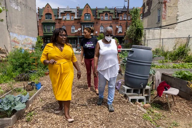 Philadelphia City Councilwoman Kendra Brooks (left) walks with Lorraine Gomez, president of Viola Street Residents Association, through the Viola Street Community Garden.