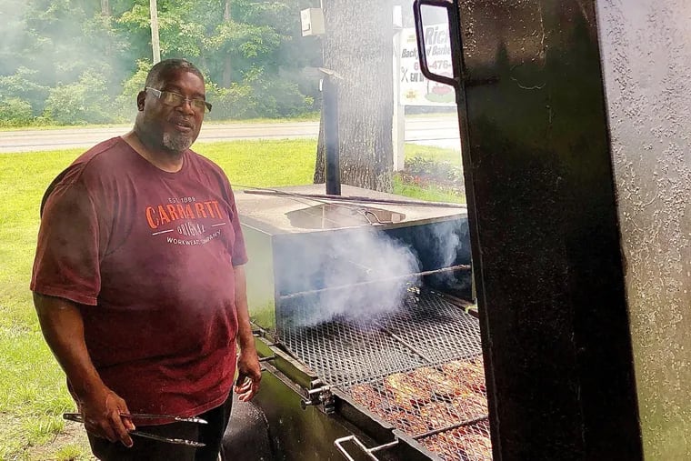 Rick Gray stands next to a smoker full of chickens at his Rick's Backyard BBQ in Mizpah. located in the Route 40 pavillion where Uncle Dewey's operated for over two decades.