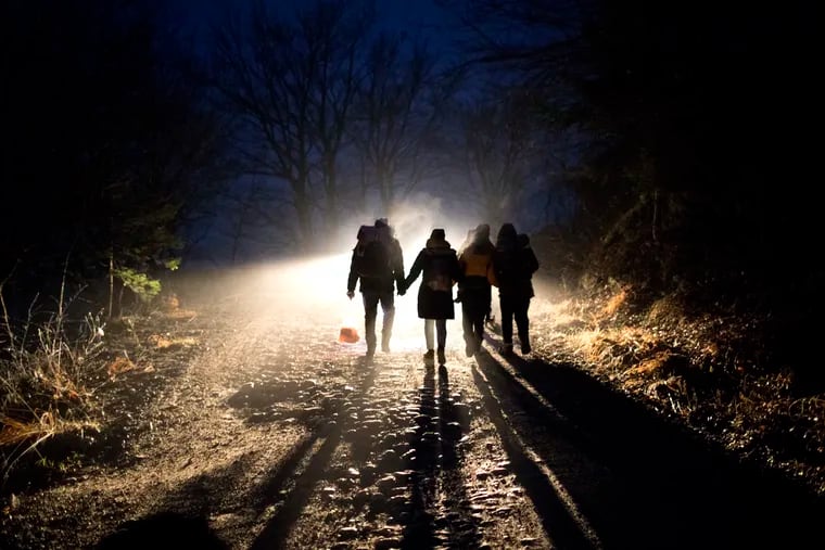 In this picture taken Thursday Dec. 12, 2019, Indian migrants Nishademi, 22, and Suhil, 23, walk with Saif, 33, Fatma, 24, and their son Omar, 1, Syrian refugees form Aleppo walk towards the border with Croatia as they attempt to enter the European Union in the mountains surrounding the town of Bihac, northwestern Bosnia.