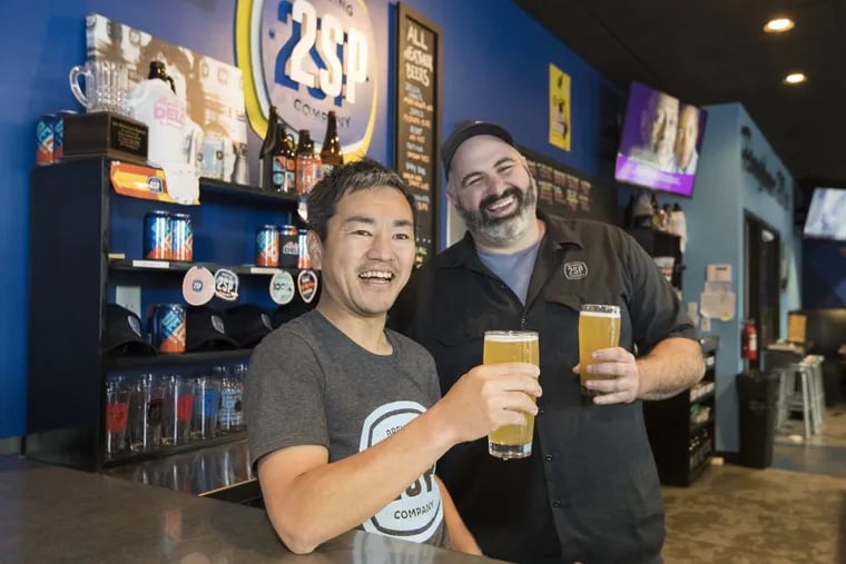 Hoisting tall ones at 2SP Brewing Co. are Michael Contreras (right), director of sales and marketing, and Junnosuke Nakamura, a beer distributor in Japan. The two met in graduate school in California and formed a friendship around beer and rugby that has become a business partnership