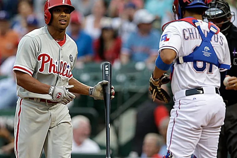 The Phillies' Ben Revere walks back to the dugout past the Rangers' Robinson Chirinos and home plate umpire Doug Eddings after striking out in the first inning. (Tony Gutierrez/AP)