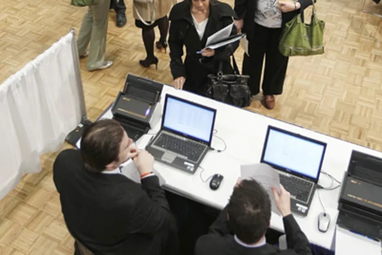 Rachel Schachter of Albany, center, waits as her resume is scanned into a New York State Department of Labor computer during a career fair at the Empire State Convention Center in Albany, N.Y., on Thursday, April 12, 2012. (AP Photo/Mike Groll)