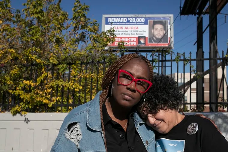 Mykia Capers, left, and Elsa Alicea underneath a billboard asking for information and a reward regarding the shooting death of Alicea’s son, Luis Martin Alicea, at the corner of 5th and Hunting Park Ave. in North Philadelphia on Tuesday, Nov. 9, 2021. Capers, a mother whose son was also shot and killed in 2016, raised money to help put up the billboard for Alicea.