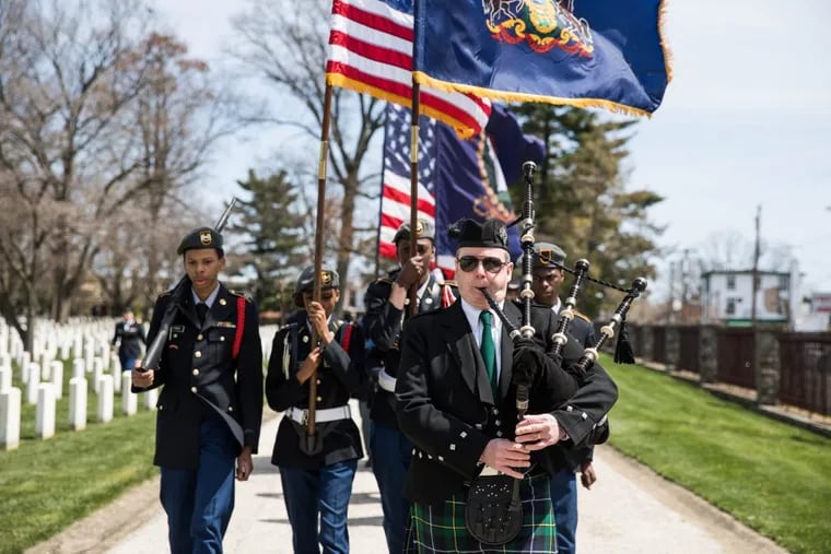 A bagpiper leads Martin Luther King High School Junior Reserve Officer Training Cadets and others in a procession through the Philadelphia National Cemetery for the  dedication of a new storyboard honoring the U.S. Colored Troops (USCT).