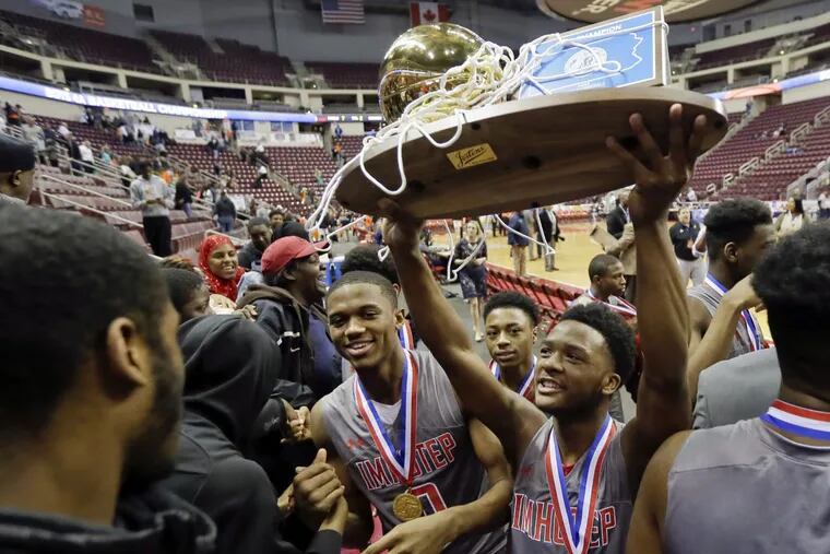 Imhotep players celebrate with the championship trophy after beating Sharon, 71-35, Monday in Hershey for the PIAA Class 4A boys’ basketball title.