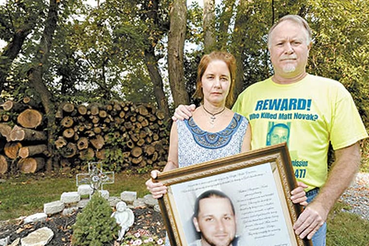 Sue and Matt Novak stand in front of a memorial garden holding a photo of their murdered son Matthew. Matthew was 24-years-old when he was killed at random in Philadelphia after watching the Puerto Rican parade in 2008. The Novaks are sponsoring a picnic on Saturday at Tall Pines Picnics and Retreat in Williamstown, NJ. (Clem Murray / Staff Photographer)