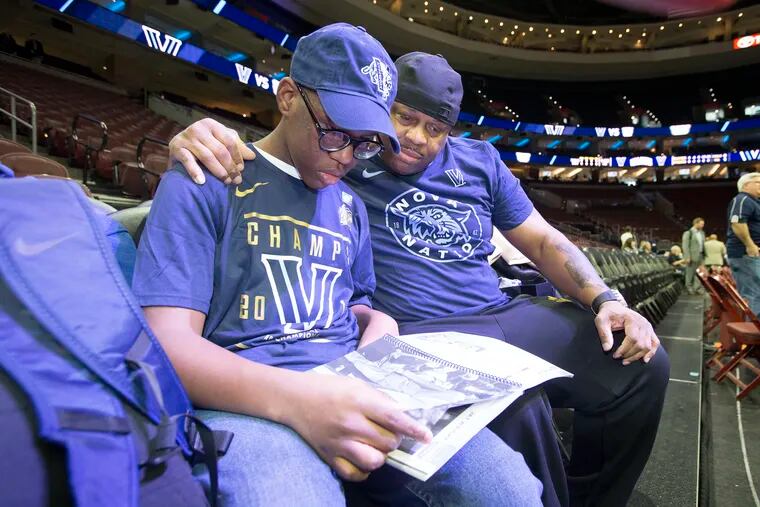 Kyle Tucker (left) and Deputy Sheriff Mike Terry go through the Villanova media guide before the game at the Wells Fargo Center Saturday -- Terry's surprise gift to the teen after finding him lost and scared in January after he got on the wrong SEPTA bus home from school.