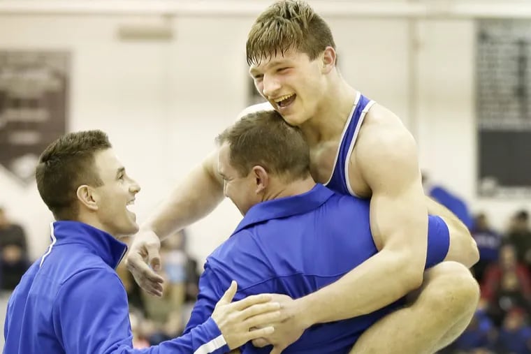 Williamstown senior Bryan Martin jumps into his coaches’ arms after winning 195-pound title at Region 8 Saturday night in Egg Harbor Township.
