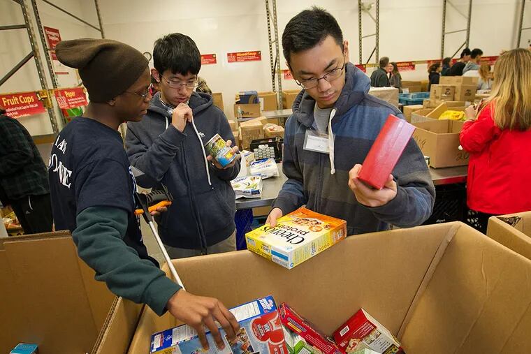 Eddie Diggs, Mark Mou, and Timothy Nerbeza, volunteers from Doane High School in Burlington, sort food at the Food Bank of South Jersey during the 21st Annual Greater Philadelphia Martin Luther King Day of Service.