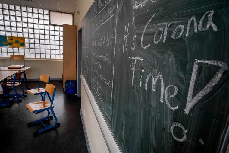 In this Friday, March 13, 2020 photo, a slogan on a chalkboard reads 'It's Corona Time' in an empty class room of a high school in Frankfurt, Germany. In the U.S. employers must pay an employee's compensation if they miss work because they need to care for a child whose school is closed due to COVID-19. (AP Photo/Michael Probst, file)