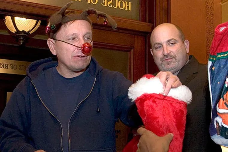 Activists Gene Stilp (left) and Eric Epstein hand Christmas stockings filled with coal to a staffer in the offices of Democratic state Reps. H. William DeWeese and Mike Veon, in Harrisburg in 2005. (DANIEL SHANKEN / ASSOCIATED PRESS /FILE)