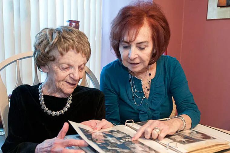 Estelle Mazis (left) and Joan Brand look through a photo album in Brand's Cherry Hill home. They have been friends for 70 years. (Ron Tarver/Staff)