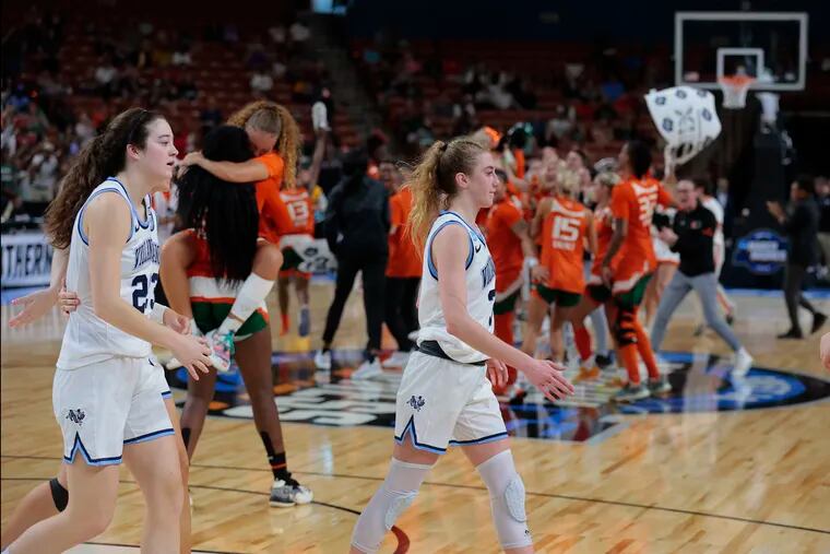 Maddy Siegrist (left) and Lucy Olsen of Villanova walk off the court as Miami celebrates in the background after their win in the Sweet Sixteen NCAA Women's Tournament game in Greenville, South Carolina on March 24, 2023.