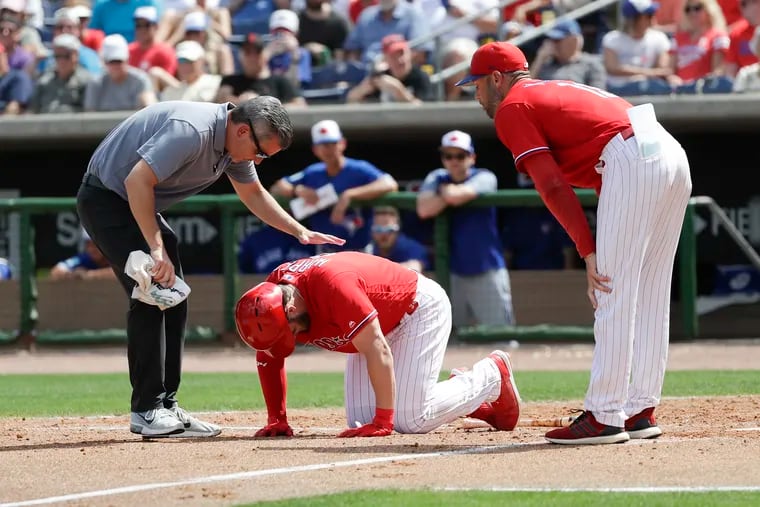 Bryce Harper is visited by Phillies manager Gabe Kapler (right) and trainer Chris Mudd after getting hit by a pitch on Friday.