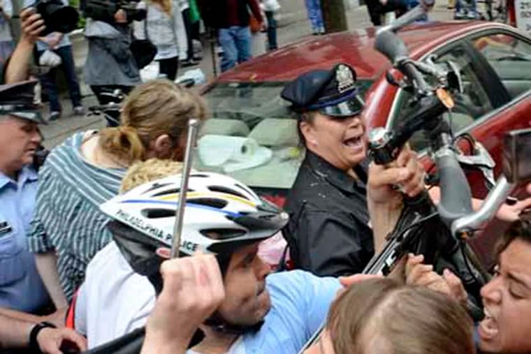 Police officers use their bicycles to keep Occupy Philadelphia members back as one is taken into custody. Occupy blocked the street outside a bank branch on Walnut Street as part of a May Day protest. TOM GRALISH / Staff Photographer