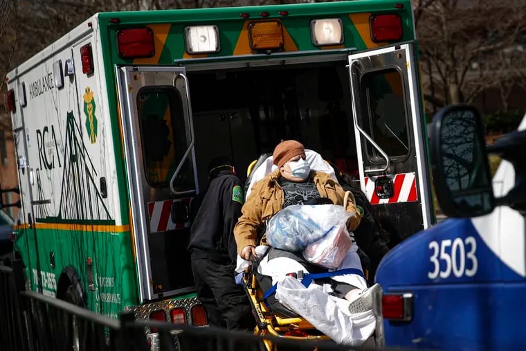 A patient wears a protective face mask as she is loaded into an ambulance at The Brooklyn Hospital Center emergency room.