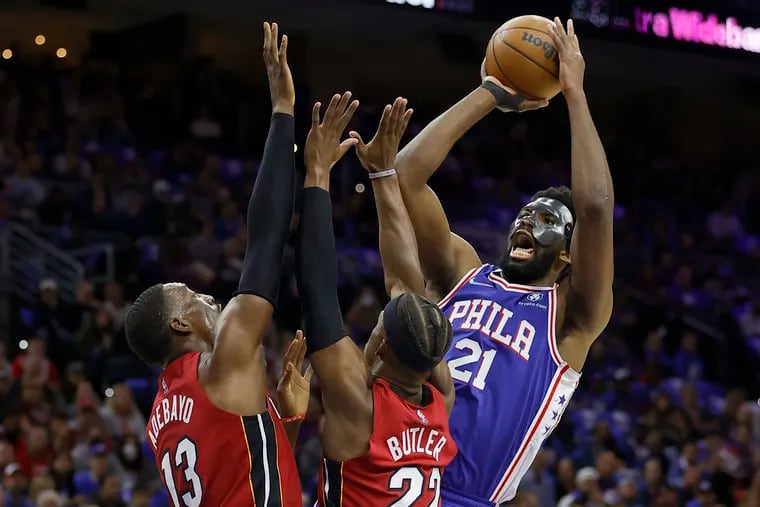 Joel Embiid, right, of the Sixers shoots over Bam Adebayo, left, and Jimmy Butler of the Heat during the first half on their playoff game at the Wells Fargo Center on May 6, 2022.