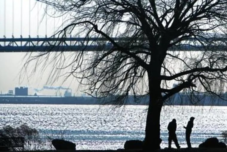 TWO MEN PAUSE under a bare tree in Penn Treaty Park along the bank of the Delaware River in the Fishtown section on Monday, a day the temperature didn&#0039;t climb out of the 20s.