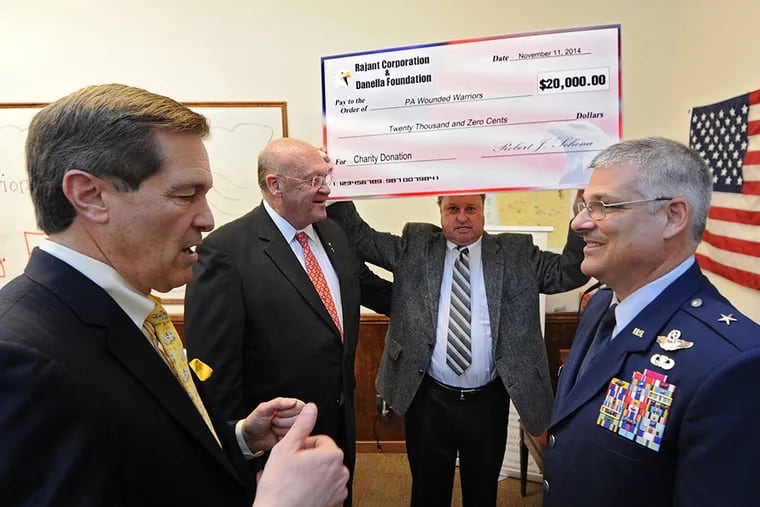 Gordon Weith, a retired Army officer and board member of the Pennsylvania Wounded Warriors, holds up an oversized check for $20,000, a donation from Rajant Corp. and its president and CEO Bob Schena (left) and the Carmen Danella Foundation, represented by trustee Rick Hevner (second from left). Brig. Gen. Anthony Carrelli of the Pennsylvania National Guard (right) spoke at the event at the Rajant office in Malvern on Nov. 11, 2014. ( CLEM MURRAY / Staff Photographer )