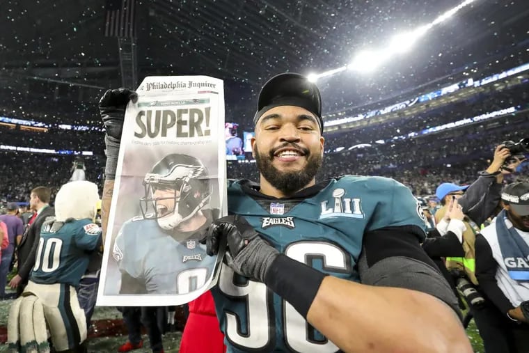 Eagles defensive end Derek Barnett holds an early mock up of an Inquirer Front page on the field after winning Super Bowl LII.