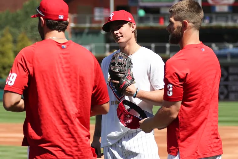 Injured Phillies center fielder Mickey Moniak (center) talks with teammates Bryce Harper (right) and Matt Vierling before the season opener.
