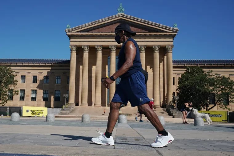 A man exercises on the the steps of the Philadelphia Art Museum, walking while using hand grip exercisers and wearing a mask, in Philadelphia, July 2, 2020. He said he has exercised on the the steps of the Philadelphia Art Museum regularly for the last 39 years.