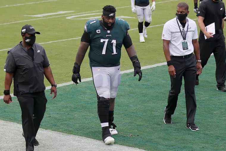 Jason Peters walks off the field with Eagles staff after Sunday's tie against Cincinnati. The veteran tackle has struggled to keep up so far this season.