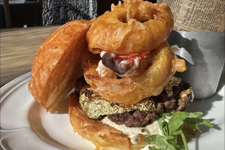 The Fireman Burger ($99) at Hook & Ladder Sky Bar & Kitchen features a Wagyu patty wrapped in gold, butter-poached lobster tail, arugula, onion rings, truffle aioli, Super Sharp three-year aged Cheddar bechamel sauce, and fresh shaved truffle.