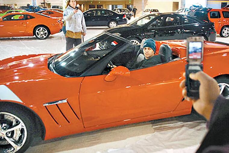 Carpenter Anthony Lucia of Blackwood, N.J., poses in a 2010 Corvette GS Convertable ($75,365.00) for a cell phone camera photo by fellow carpenter Terry Higgins,  of West Oak Lane, in the Pennsylvania Convention Center Thursday in preparation for the opening of the Auto Show. (Tom Gralish / Staff Photographer)