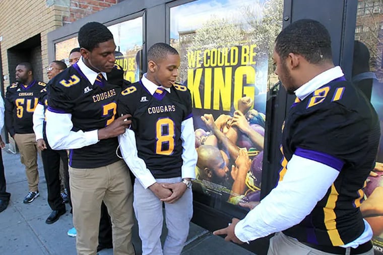 (Left to right) D.J. Brinkley, Emmanuel Clark, and Joseph Walker, members of the Martin Luther King High School football team, check out movie posters outside of Sunshine Cinema in lower Manhattan. The premiere of "We Could Be King " was held during the Tribeca Film Festival on Wed, April 23, 2014. ( CHARLES FOX / Staff Photographer )