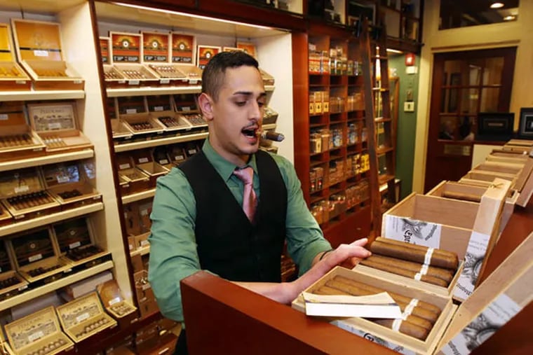 At Holt's Cigar Co. in Center City, Adam Conigliaro restocks merchandise. A store manager wasn't ready to comment on Cuban cigars' becoming legal for sale in the U.S. "until anything becomes official."