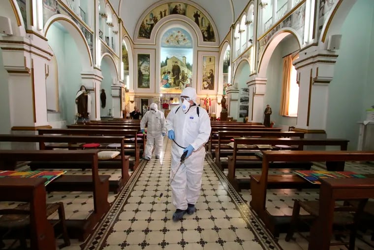 Workers wearing protective clothing disinfect St Antonio Church, in Bayrakli district of Izmir, Turkey, on Thursday, as a precaution against the coronavirus.