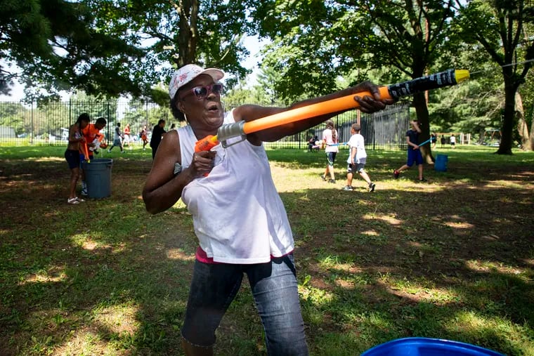 Mary Tillery, 60, center, of North Philadelphia, Pa., raises a her super soaker to spray someone during the Water Fight Philly event at West Fairmount Park on Saturday, July 20, 2019. Tillery intended to be here with her family and was having fun.
