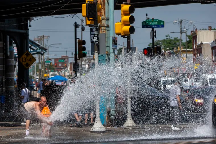 An open fire hydrant along Allegheny Avenue at Kensington Avenue in Philadelphia helps people cool off.