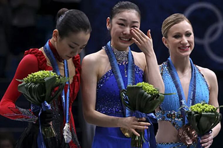 Gold medallist Kim Yu-Na of South Korea, center, reacts as she stands on the podium with silver medallist Mao Asada of Japan, left, and bronze medallist Joannie Rochette of Canada, right, during the medal ceremony for the women's figure skating competition. (AP Photo/Mark Baker)