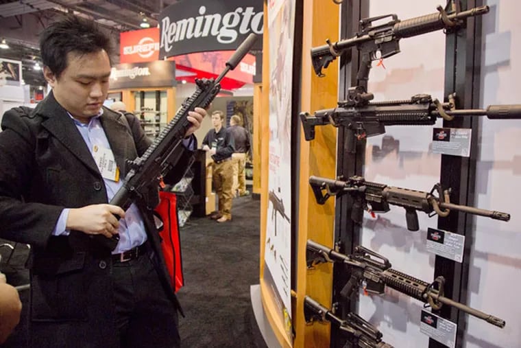 Accessories manufacturer Kevin Kao, of Irvine, Calif., examines a military grade Remington Adaptive Combat Rifle at the  35th annual SHOT Show, Tuesday, Jan. 15, 2013, in Las Vegas. The National Shooting Sports Foundation was focusing its 35th annual SHOT Show on products and services new to what it calls a $4.1 billion industry, with a nod to a raging national debate over assault weapons.  (AP Photo/Julie Jacobson)